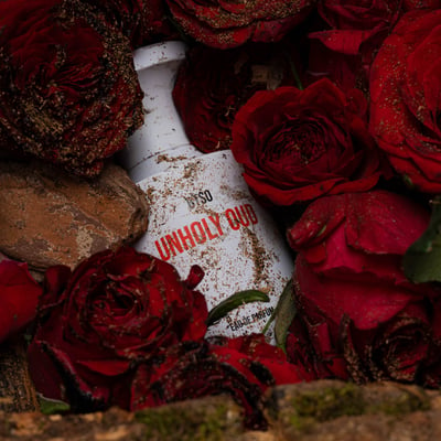 赤い薔薇の花の下に埋まる白い香水ボトル