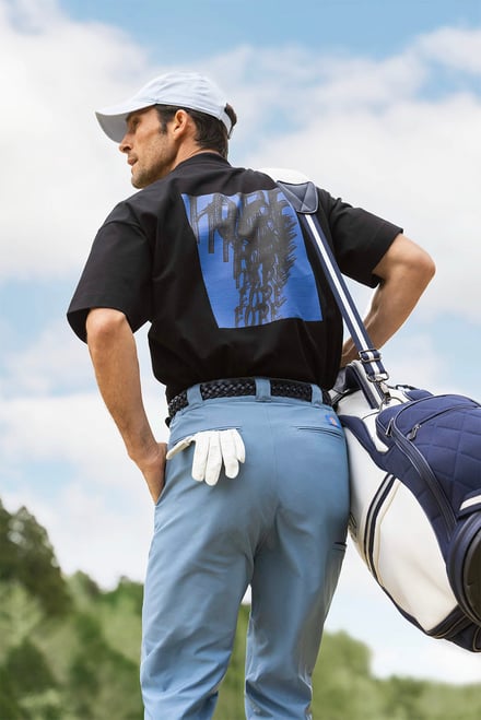 ゴルフウェアを着てゴルフバッグを担いだ男性モデル