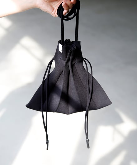 黒の巾着型ニットバッグとモデルの手