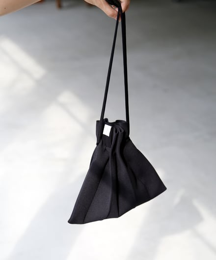 黒の巾着型ニットバッグとモデルの手