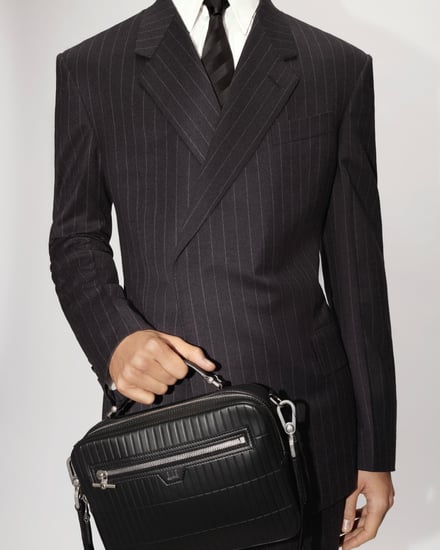 ハンドバッグを手に持つスーツ姿の男性モデル