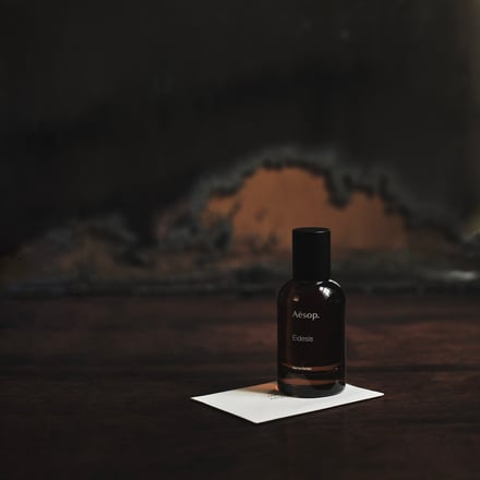 暗めの空間に茶色のガラスに入っている香水のビジュアル
