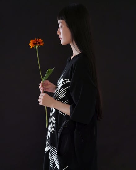 黒いTシャツを着て花を持つ女性モデル