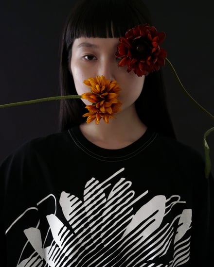黒いTシャツを着て花を持つ女性モデル