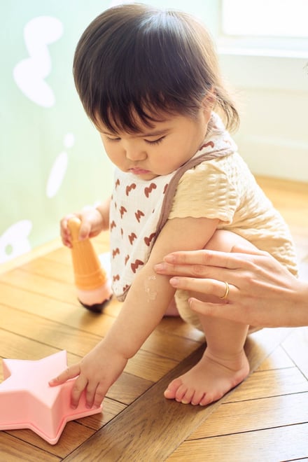 ピンクの星のおもちゃを触る赤ちゃんと大人の手