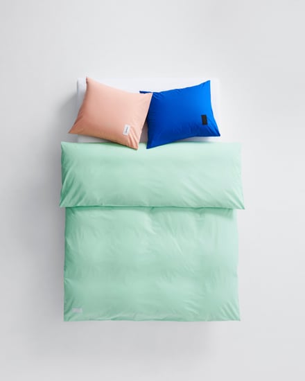 緑のシーツカバーとオレンジと青のピローケースを使用したベッドベッド