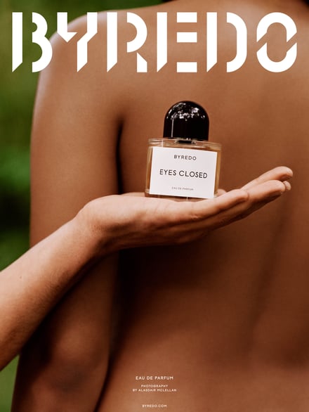人間の裸の背中を背景に香水が手に持って置かれている様子
