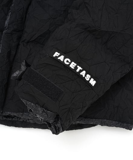 黒いジャケットの袖にあしらわれたファセッタズムの白いロゴ