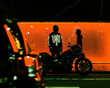 黒いヘルメットとジャケットを着用してバイクの横に立つ人