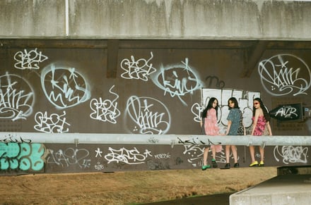 落書きが描かれた壁を背景にした3人の女性