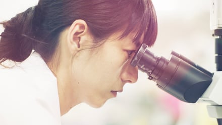 顕微鏡に目を当てる女性