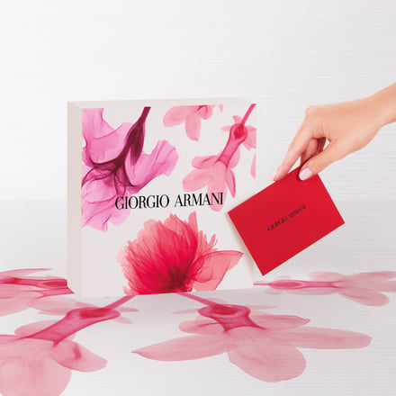 白地にピンクや赤の花がプリントされた箱と赤いメッセージカードを持つ手