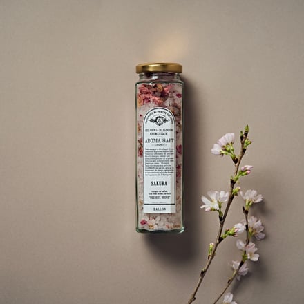 中央にガラス瓶に入ったバスソルトとその右横に花が咲いた桜の切り枝