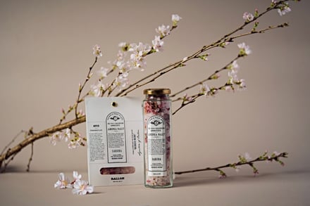 花が咲いた桜の切り枝とバスソルトの商品ボトルを映した写真