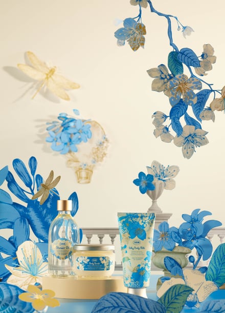 青い花やトンボなどが集まった背景にクリームと青のデザインの化粧品が並んでいる様子