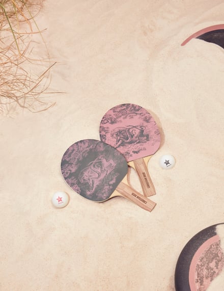 砂浜に置かれたDIORの卓球ラケットセット