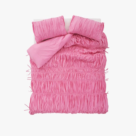 ピンクの布団カバーをかけたベッド