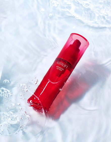 水を背景に赤いボトルの化粧水が映る写真