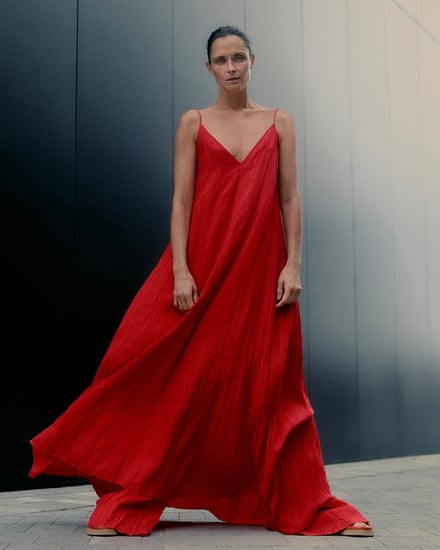 黒色の壁の前に立つモデル、赤色の服