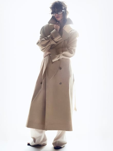 白い背景、ベージュのコートを着たモデル