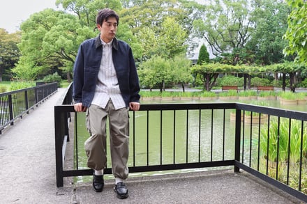 ネイビーのジャケットに白いシャツ、カーキのカーゴパンツとローファーを履いた男性