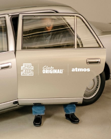 デザートブーツを履いた男性が白い車から降りてくる様子