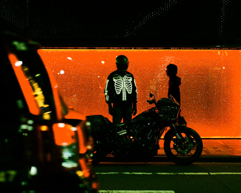 黒いヘルメットとジャケットを着用してバイクの横に立つ人