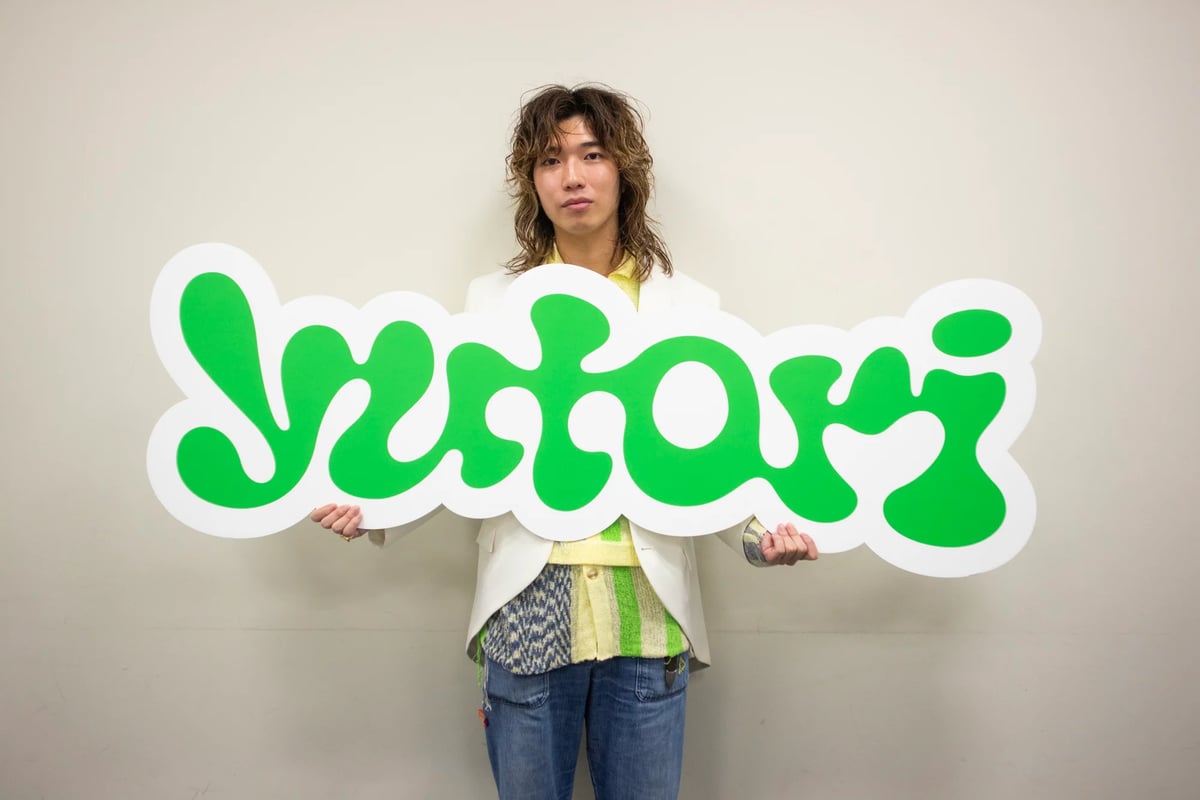 yutoriのロゴパネルを持った片石貴展代表