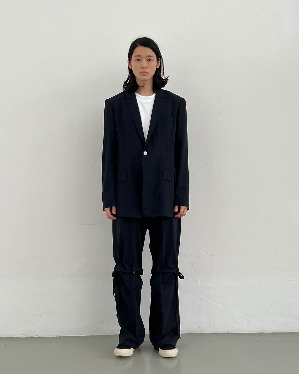 黒一色のジャケットセットアップを着用した男性モデルの全身ショット