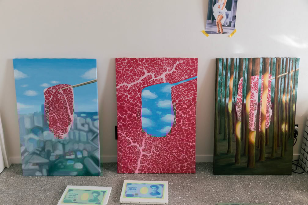 箸で持ち上げられた生肉を描くアーティスト田辺の作品