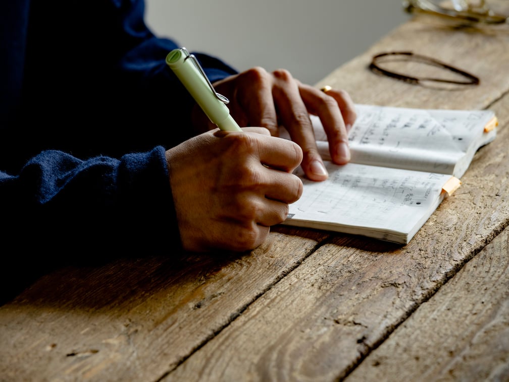 ノートに書き込む男性の手元