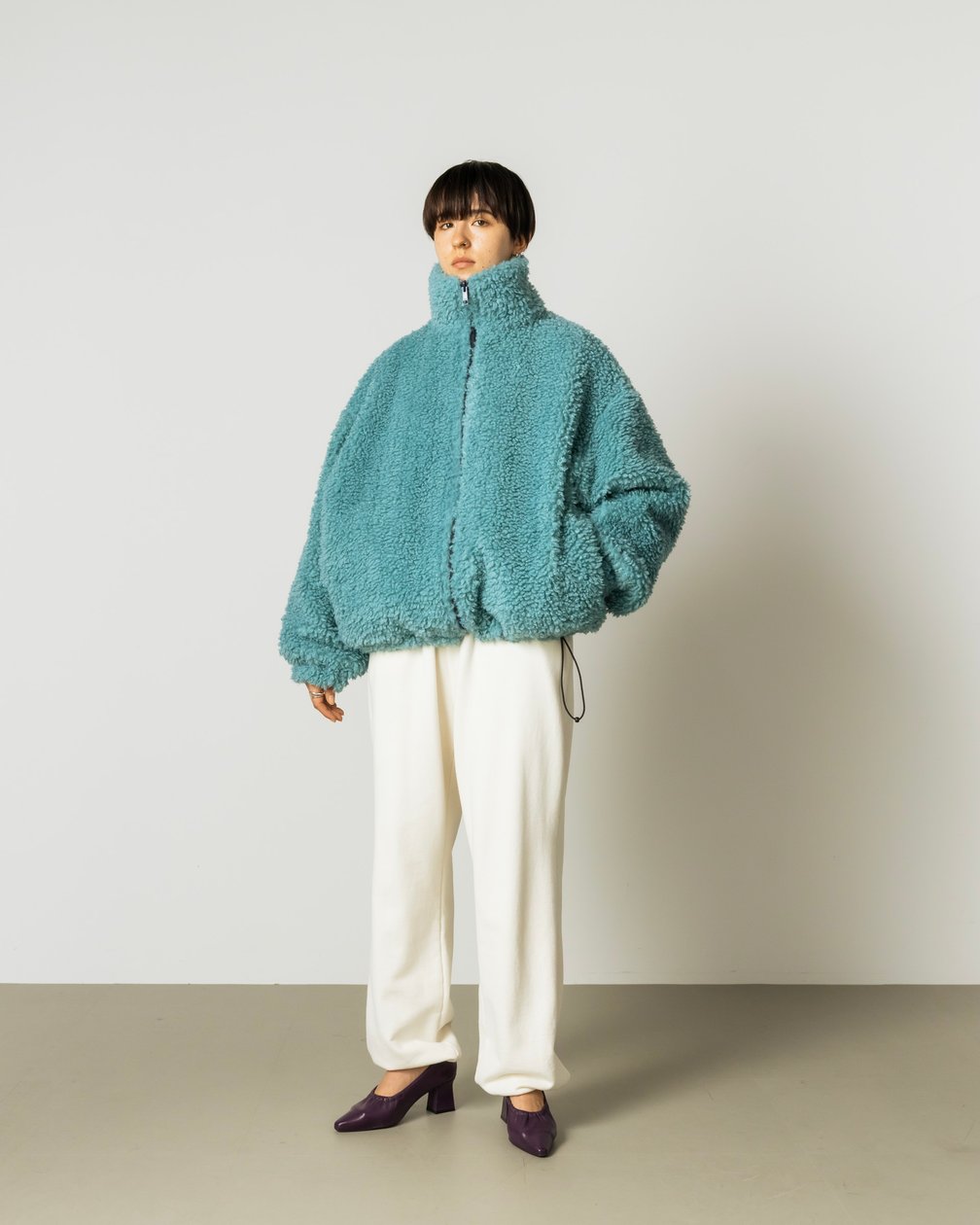 ブルーのカーリーブルゾンを合わせた女性モデル