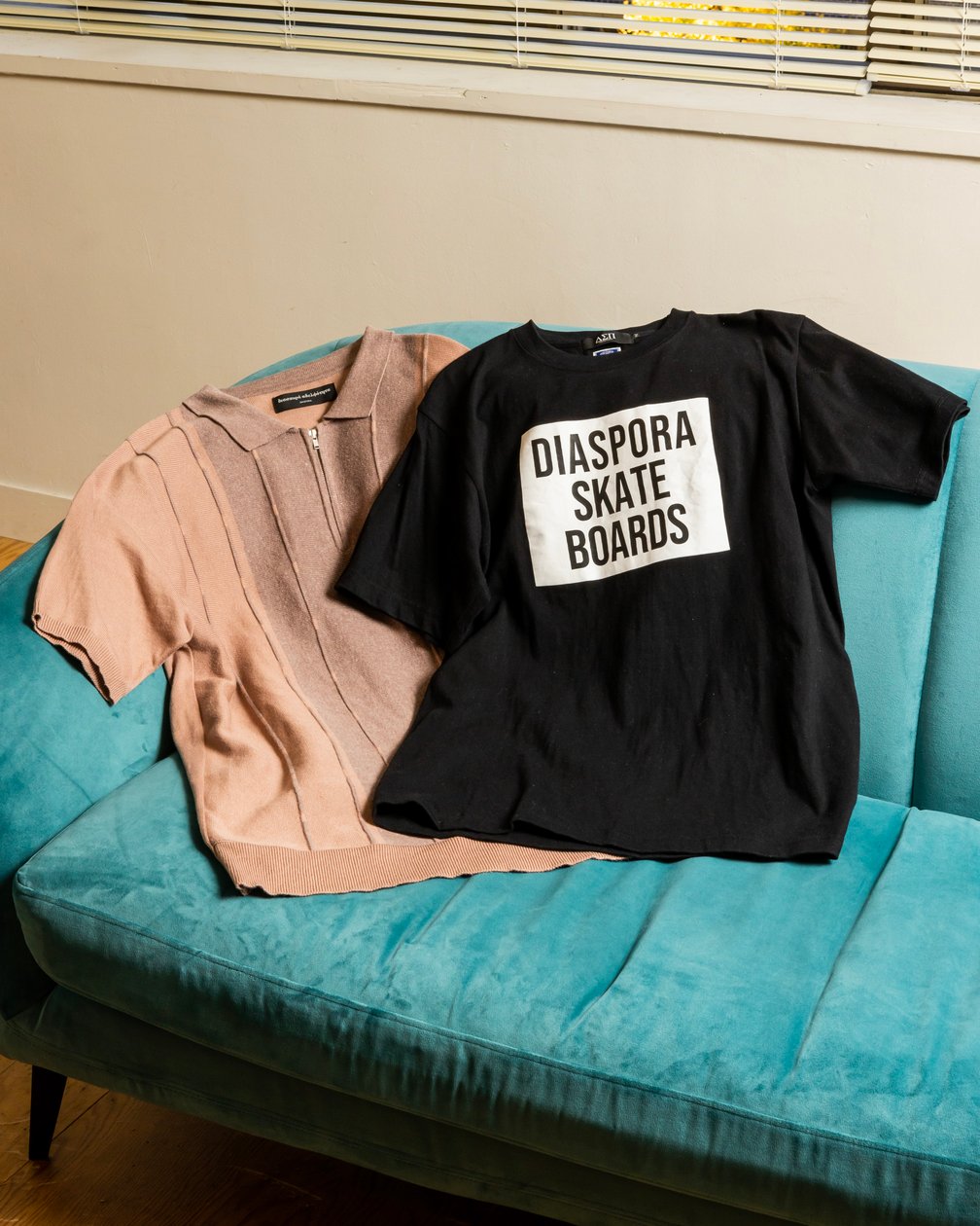 ピンクのポロニットと「ディアスポラ スケートボーズ」のロゴを配した黒いTシャツ