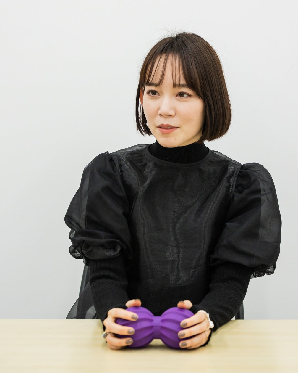 紫のマッサージボールを手に持つボブの女性