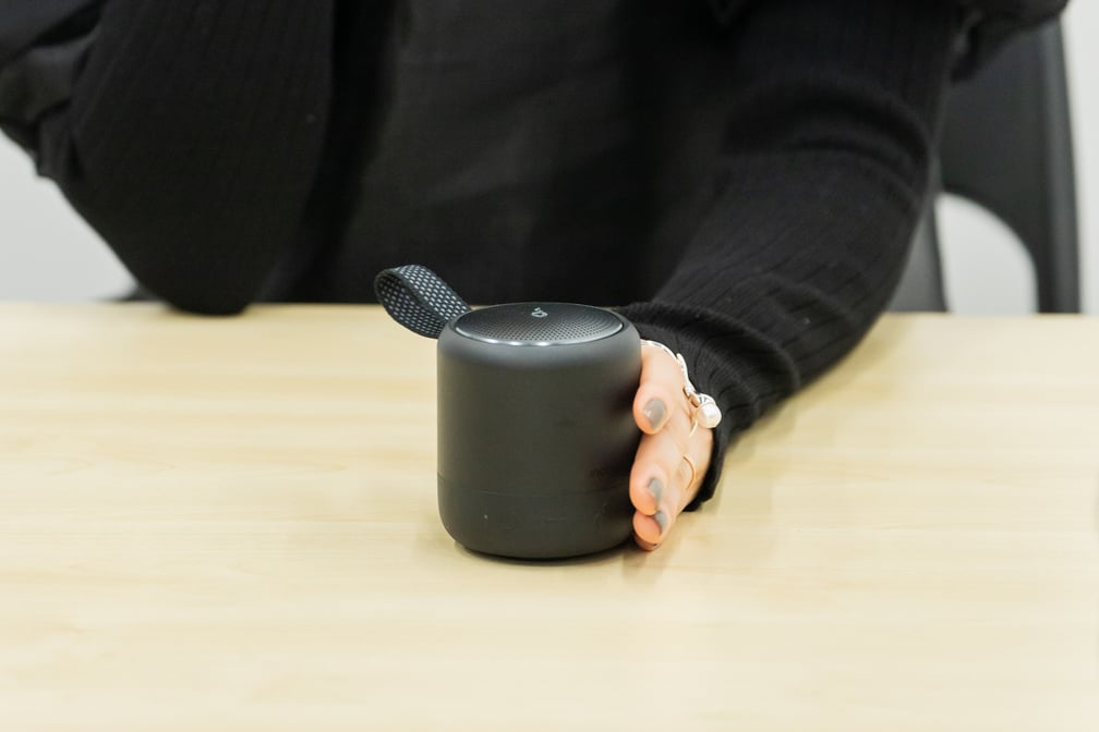 黒いコンパクトなスピーカーを手に持っている女性