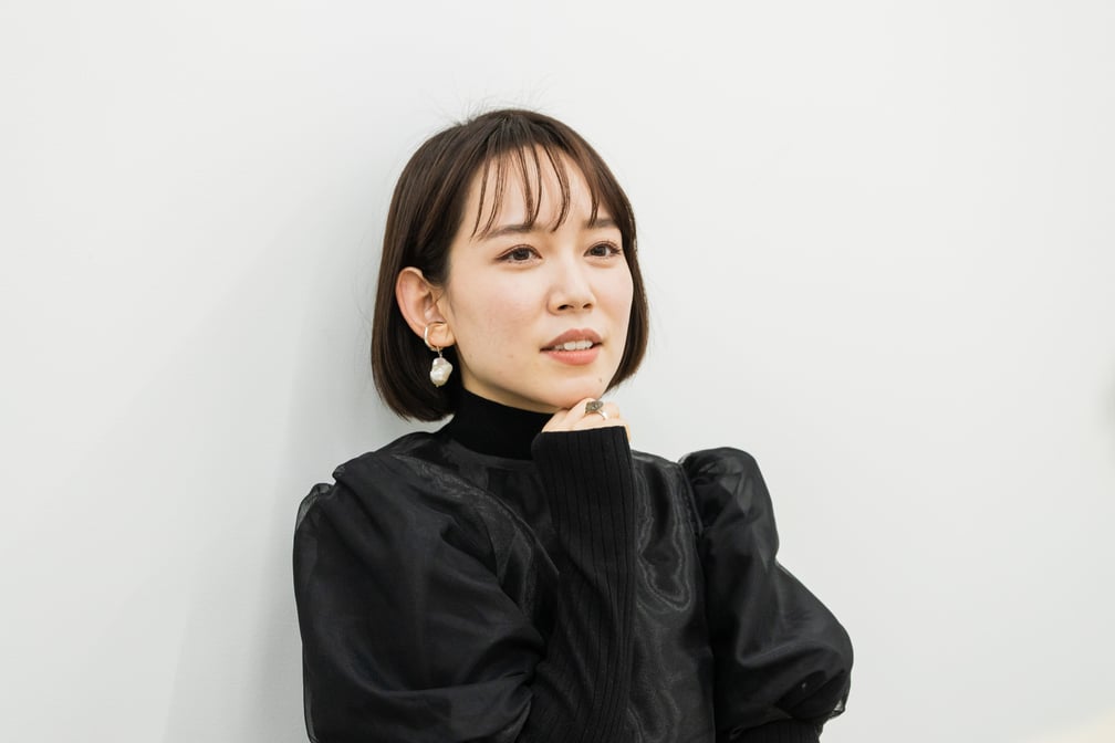 顎に手を添えて悩んでいる様子の女性