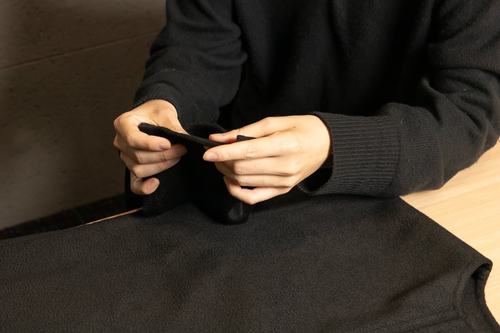 黒い生地を触るデザイナーの手元