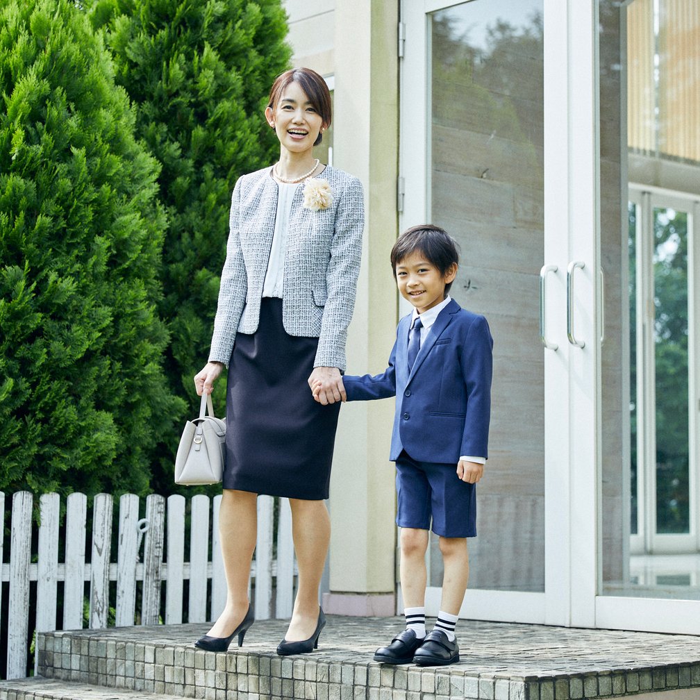 スーツを着用した子どもと手を繋ぐセレモニースーツを着用した母親