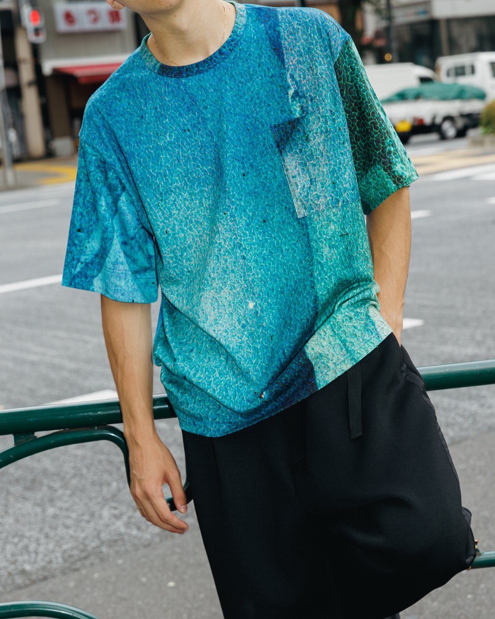 ブルーのTシャツにブラックのパンツを合わせた男性モデル