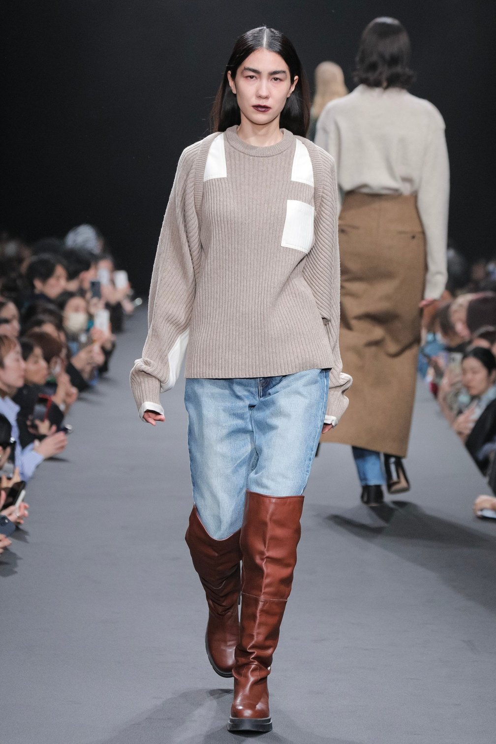 ベージュのニットにデニムを合わせた女性モデル