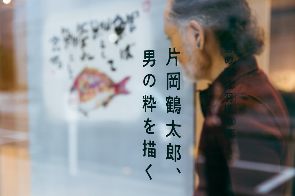 作品を背景にインタビューに応じる片岡鶴太郎
