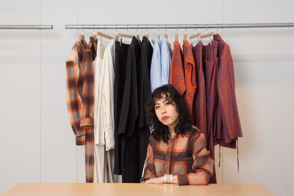 商品の前に座る女性デザイナー