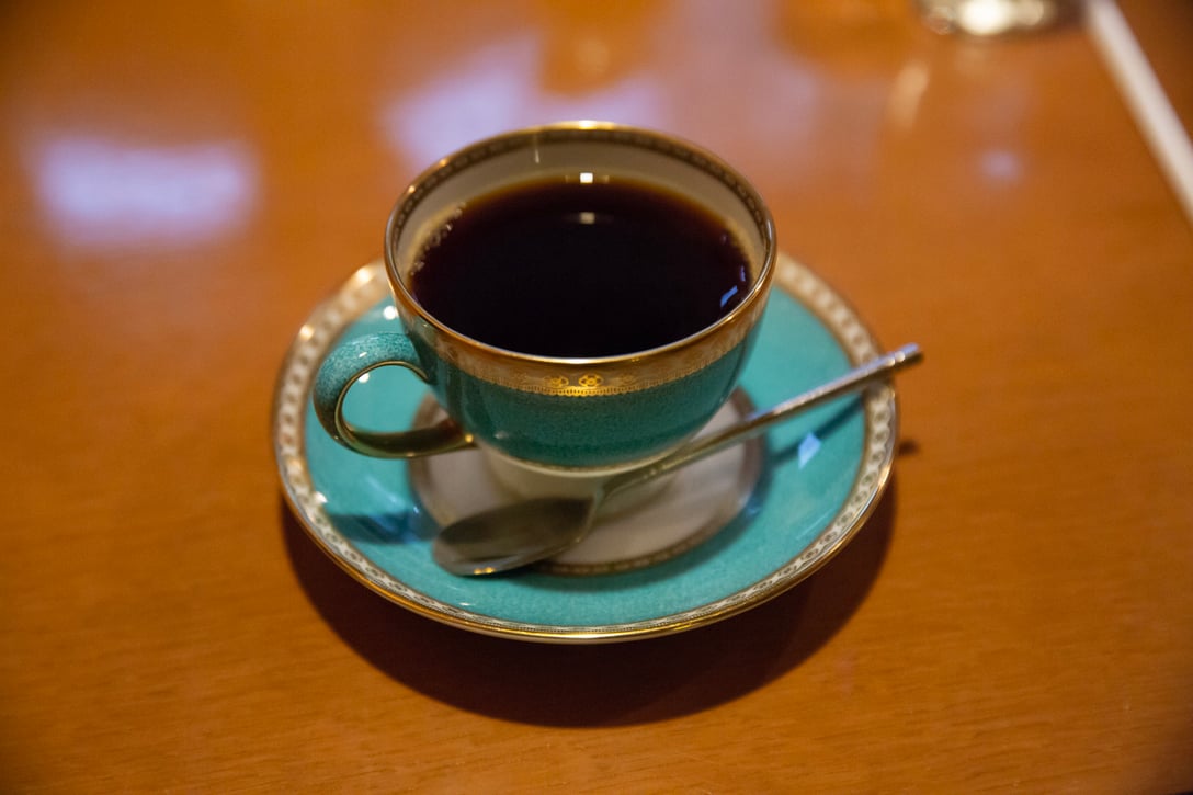 ターコイズブルーに金の縁がデザインされたコーヒーカップ