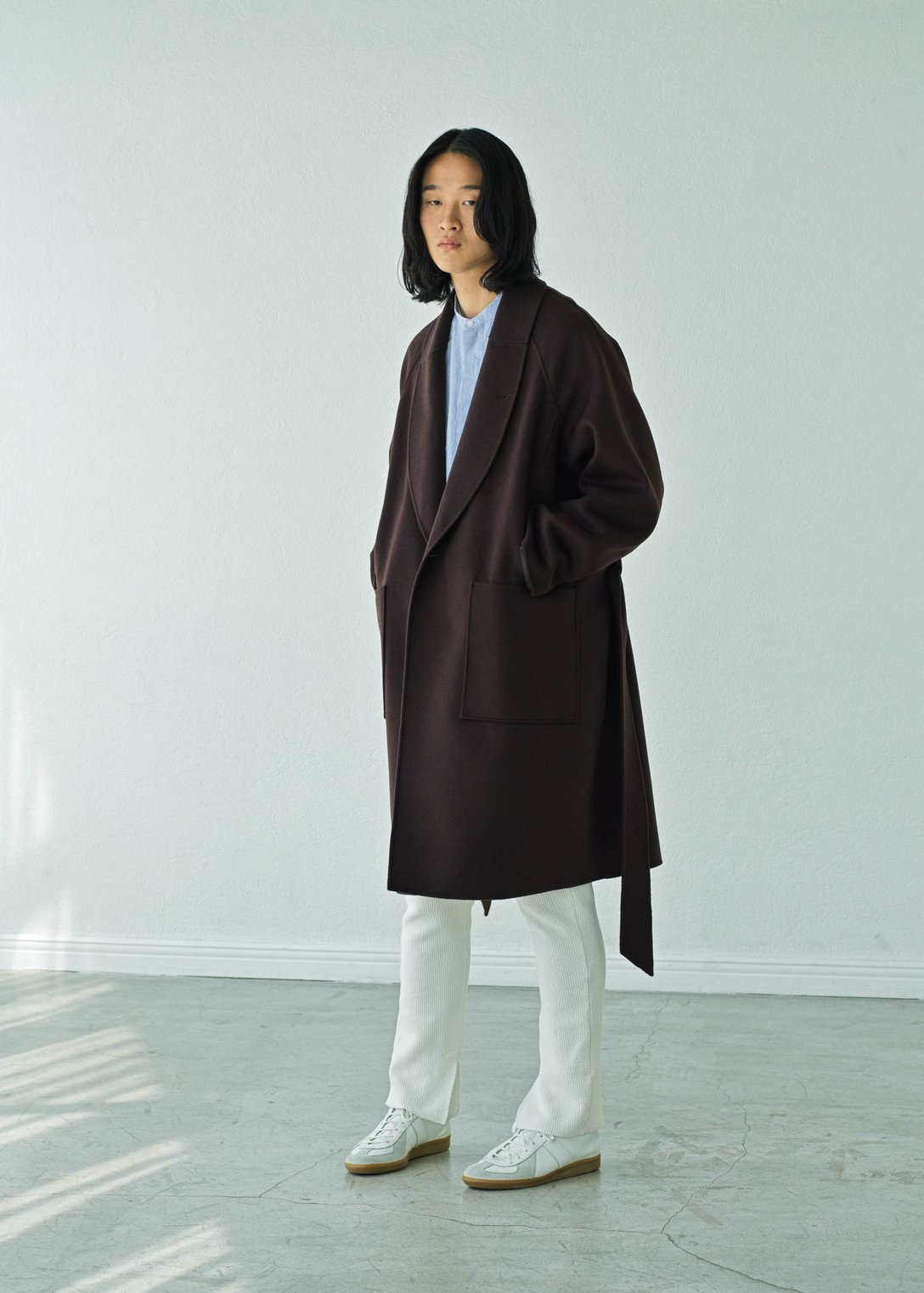 ブラウンのロングコートを着用する男性モデル