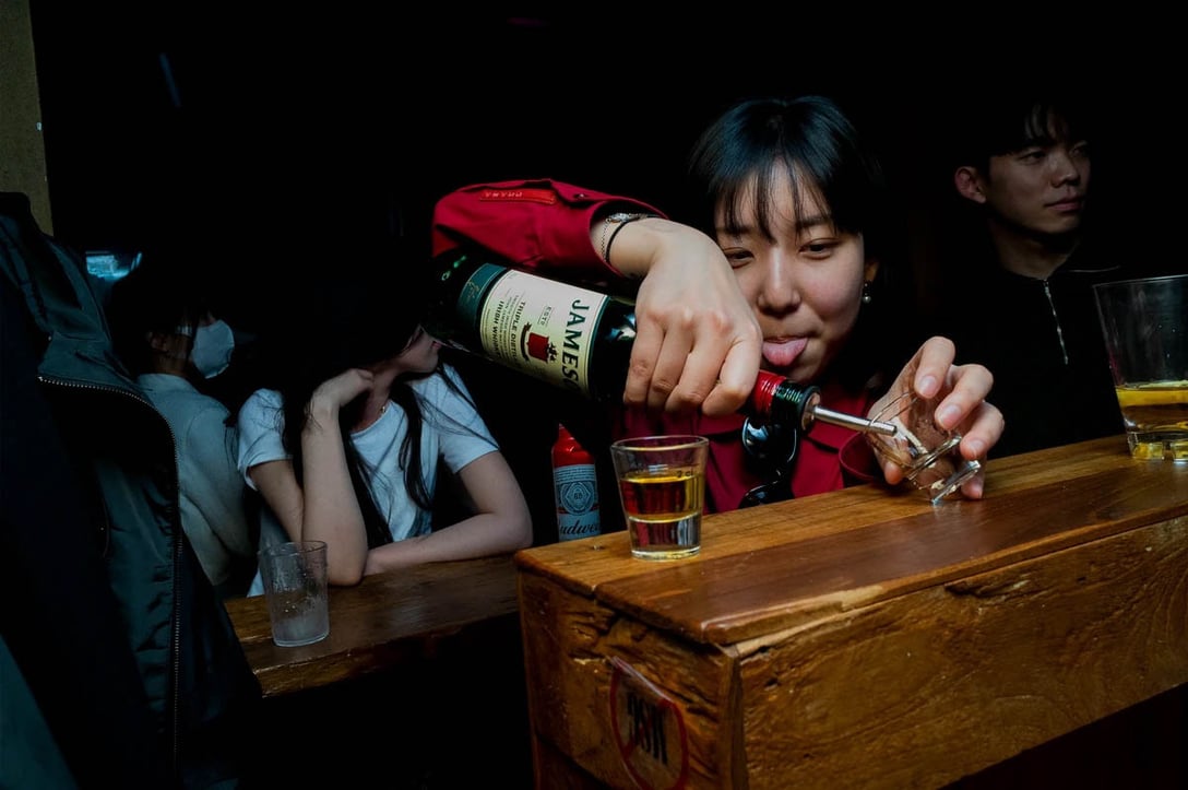 ソウル、梨泰院のルーフトップバー〈PAPER〉にて、ショットグラスに酒をつぐ若い女性。5月1日。PHOTO: YUNBEOM BAE