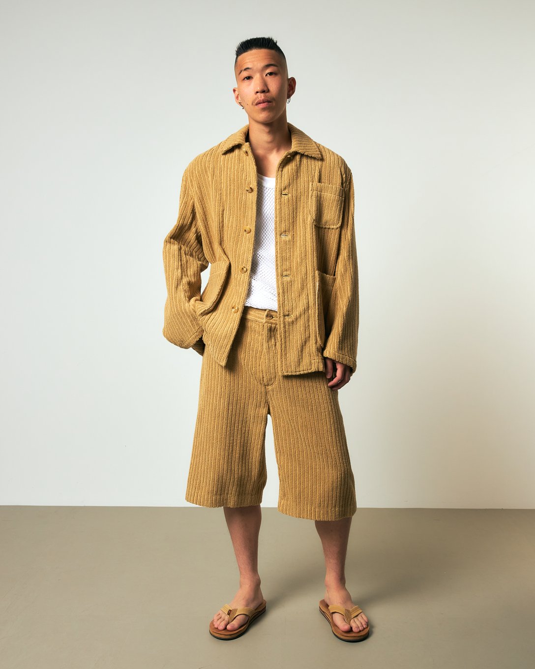 ベージュのパイルジャケットとパンツのセットアップを着た男性モデル