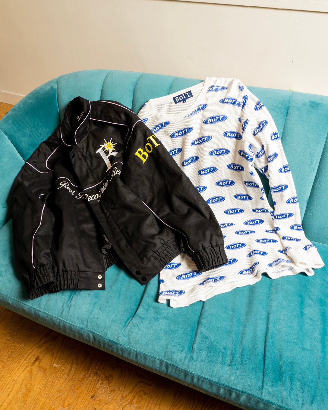 黒いジャケットと青いロゴの総柄を配した白いカットソー