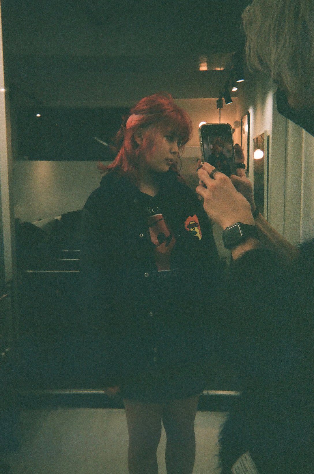 赤髪の女性のヘアスタイリングを携帯で撮っている様子