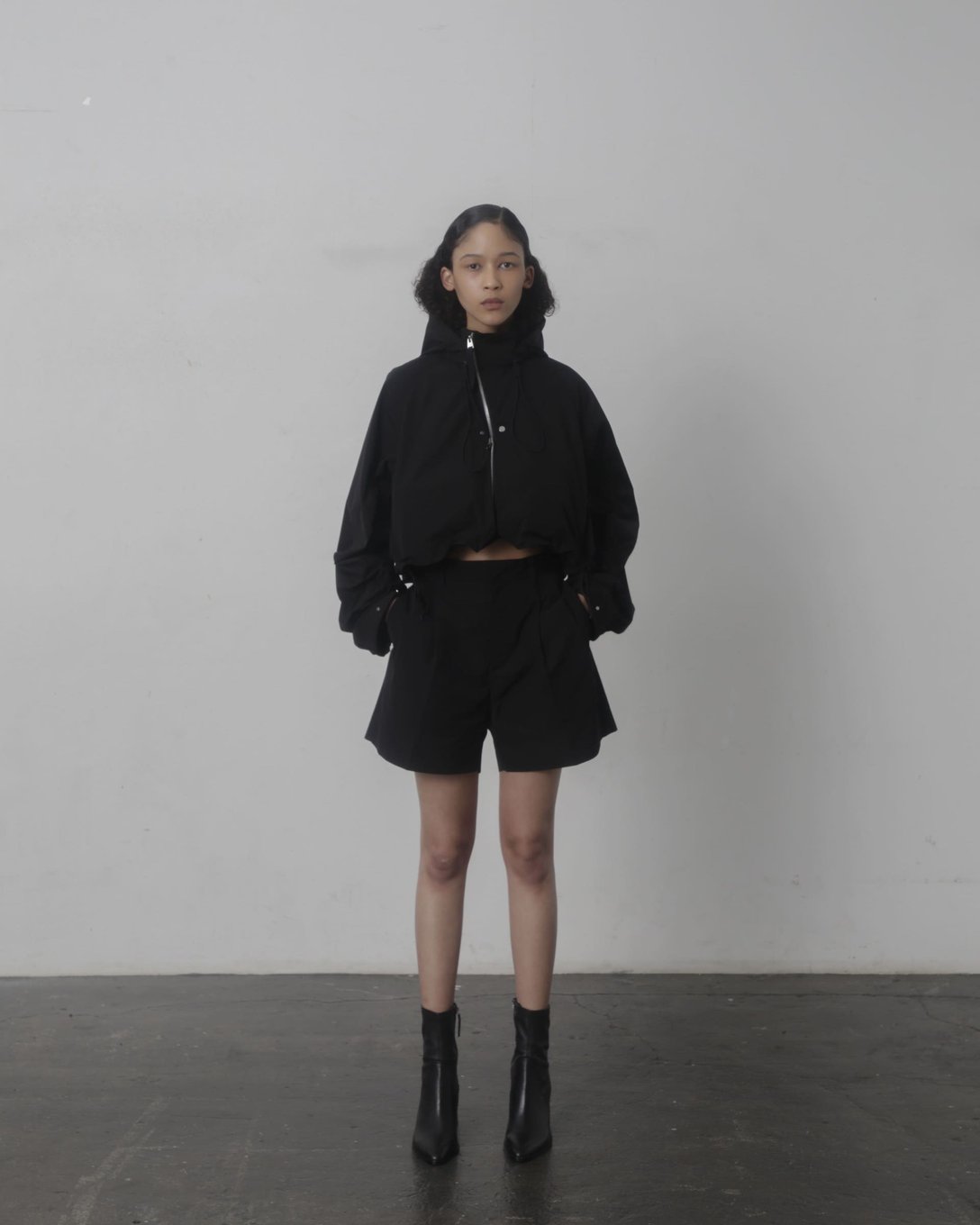 ブラックのクロップドジャケットとショーツを着用した女性モデル