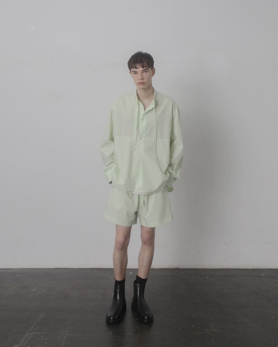 ライトグリーンのプルオーバーシャツを着用した男性モデル
